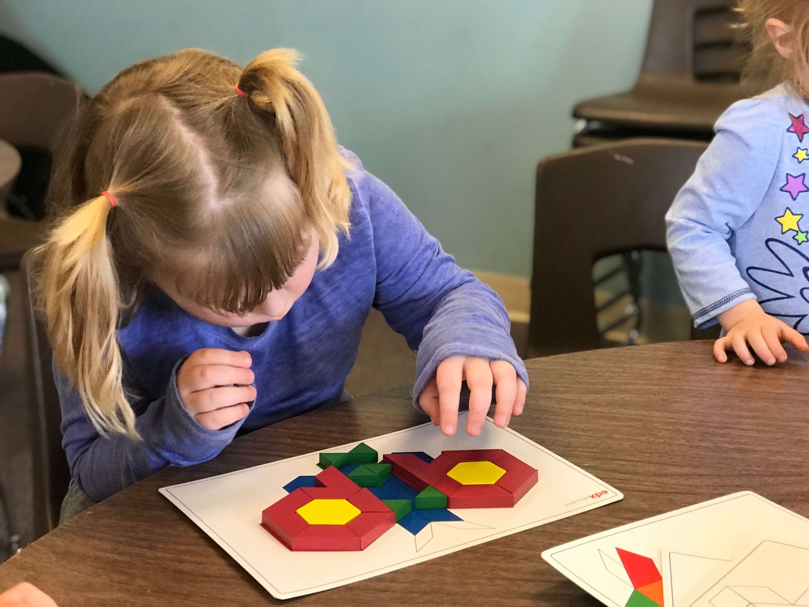 Child using pattern blocks and pattern card.
