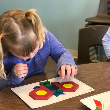 Child using pattern blocks and pattern card.
